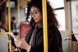 Landscape image of female wearing glasses whilst on public transport 