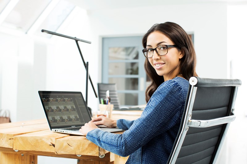 Female sat behind laptop screen wearing eyeglasses